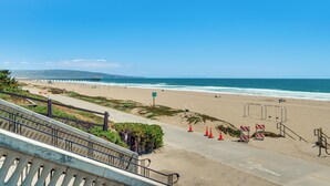 A beach with a pier, a staircase leading down to the beach, and orange traffic cones. - Steps to Ocean: Manhattan Beach Gem w/ Deck! (Manhattan Beach)