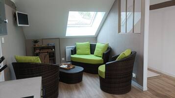 Une pièce confortable de style loft, dotée d'un puits de lumière, de meubles en osier et d'une petite kitchenette.