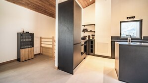 Una cocina moderna con techo de madera, una estantería empotrada para vinos y un amplio ventanal con vistas al exterior.