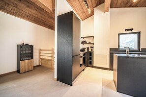 A modern kitchen with a wooden ceiling, a built-in wine rack, and a large window offering a view of the outdoors.