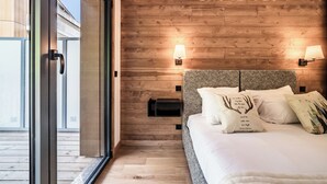 Un dormitorio con cabecera de madera, una cama con ropa de cama blanca, dos lámparas de noche y una mesita de noche negra.