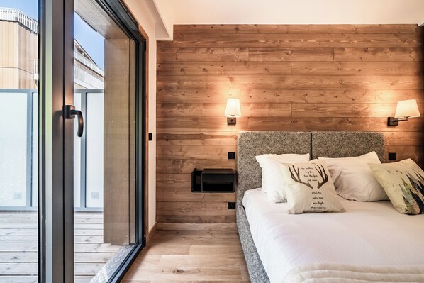 A bedroom with a wooden headboard, a bed with white bedding, two bedside lamps, and a small black nightstand.