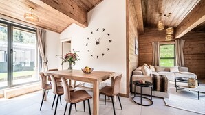 Una sala de estar moderna con techo de madera, un comedor con mesa y sillas de madera, y un gran reloj de pared.