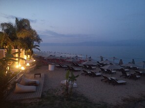 A beachside resort with sun loungers, umbrellas, and a wooden deck area.
