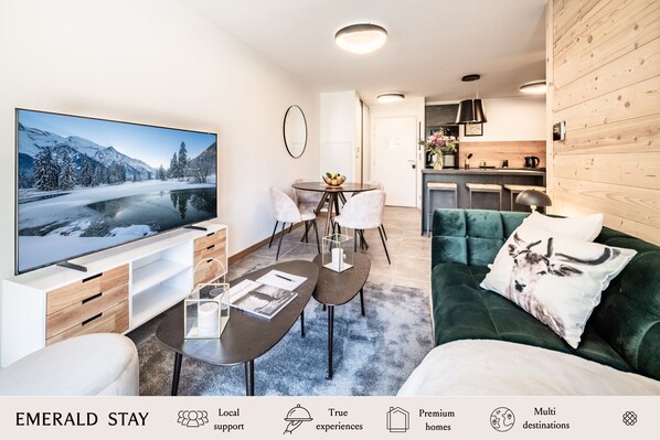 Una sala de estar moderna con televisor grande, comedor y cocina.