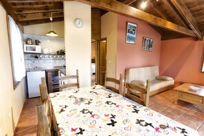 Una habitación acogedora con una cama, una mesa de madera, una silla, una pequeña kitchenette y un reloj en la pared.