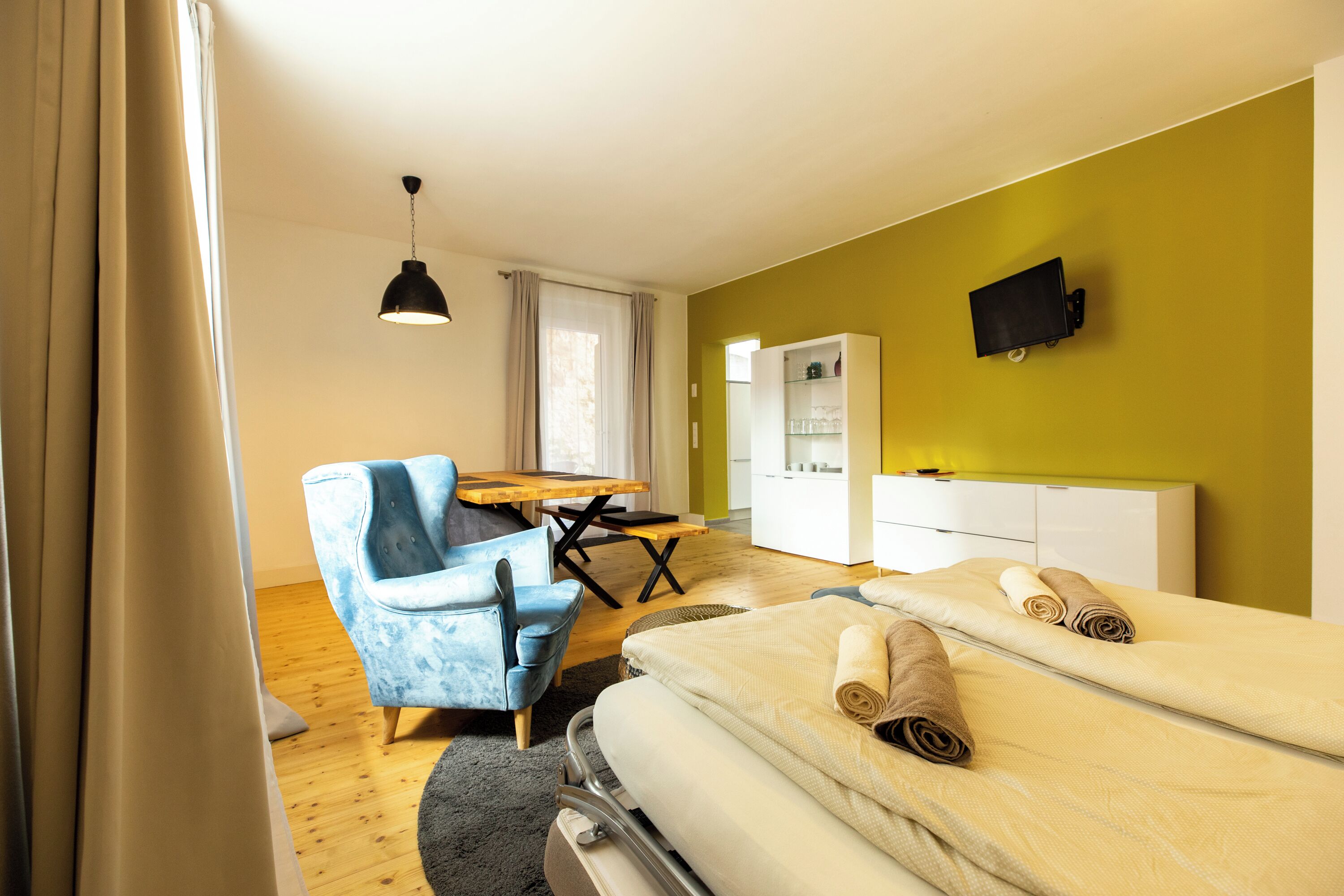 Ein Hotelzimmer mit Bett, Schreibtisch, Stuhl, Fernseher und Kleiderschrank.