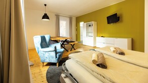 Ein Hotelzimmer mit Bett, Schreibtisch, Stuhl, Fernseher und Kleiderschrank.