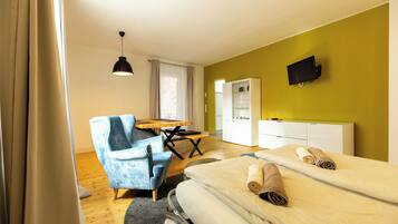 Ein Hotelzimmer mit Bett, Schreibtisch, Stuhl, Fernseher und Kleiderschrank.