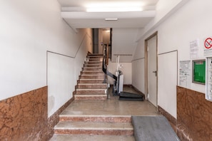 A staircase leading to an upper floor, with a handrail on one side and a door on the other.
