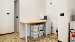 Eine kleine Küchenzeile mit Mikrowelle, Mülleimer und Papierkörben.