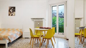 Ein Zimmer mit einem Bett, einem Tisch mit Stühlen, einer Heizung und einem Fenster mit Blick auf Grünflächen.