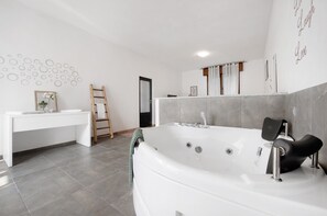 Une salle de bain moderne avec une grande baignoire, un meuble-lavabo avec un miroir et un porte-serviettes.