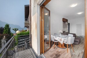 Un balcon avec une table et des chaises, un canapé et une vue sur les montagnes.