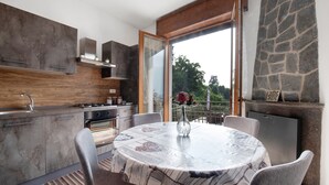 A modern kitchen with a dining area, large windows, and a stone accent wall. - Apartment 'Dudi Jolie' with Lake View, Whirlpool, Terrace and Wi-Fi (Lezzeno)