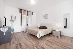 Une chambre à coucher comprenant un lit, des tables de chevet, une commode et une fenêtre avec des rideaux.