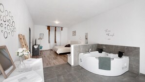 A modern bathroom with a large bathtub, a shower area, and a separate bedroom with a bed and curtains. - Apartment 'Dudi Jolie' with Lake View, Whirlpool, Terrace and Wi-Fi (Lezzeno)