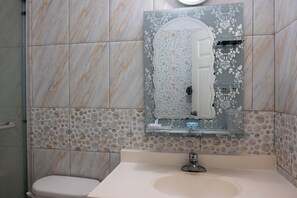 A bathroom with a marble wall, a sink, and a toilet. - The Carhampton Villa (Montego Bay)