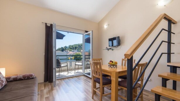 A modern apartment with a balcony, a dining area, and a staircase.