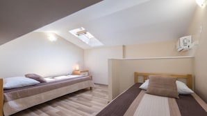 A bedroom with two beds, a skylight, and a ceiling fan.