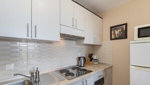 A compact kitchen with white cabinets, a stainless steel sink, a gas stove, and a microwave. - Apartments Nmn - Studio Apartment with Balcony 3 (Drvenik)
