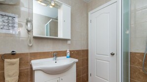 A bathroom with a white sink, a mirror, a towel rack, a glass shower enclosure, and a door. - Apartments Nmn - Studio Apartment with Balcony 3 (Drvenik)