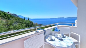 Un balcon avec une table dressée pour deux personnes, offrant une vue sur la côte.