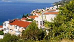 Un quartier résidentiel situé sur la côte, avec des maisons dotées de toits en tuiles rouges et de murs blancs, offrant une vue sur la mer.