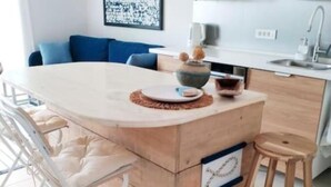 A modern kitchen with a central island, bar stools, and a seating area with a blue sofa. - Eco Feng Shui Apartment with a View- Two Bedroom Apartment with Sea View (Tkon)