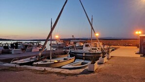 A marina with several boats docked, a paved area, and a distant view of the landscape. - Eco Feng Shui Apartment with a View- Two Bedroom Apartment with Sea View (Tkon)
