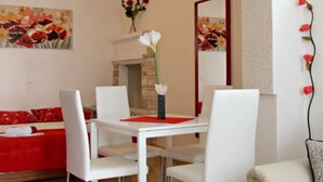 A dining area with a white table and chairs, a red sofa, and a fireplace.