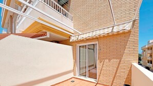 A balcony with a tiled floor, a sliding glass door, and a small potted plant.