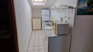 Eine schmale Küche mit Oberlicht, weißen Schränken und einer kleinen Arbeitsplatte.