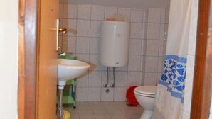 Ein kleines Badezimmer mit einem weißen Waschbecken, einer Toilette und einem weißen Wassertank.