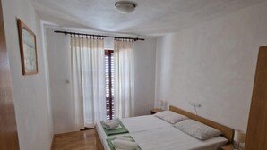 A small, clean room with a single bed, a bedside table, and a window with curtains.