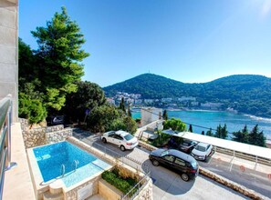 A pool area with a view of a coastal town and mountains.