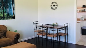 Comedor con ventilador de techo, un reloj y un cuadro de un bosque.