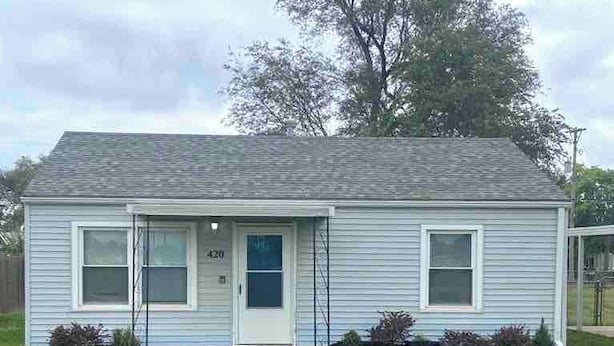 A single-story house with a front door, two windows, and a small porch area.