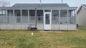 A single-story building with a covered patio area, a door, and a small window.