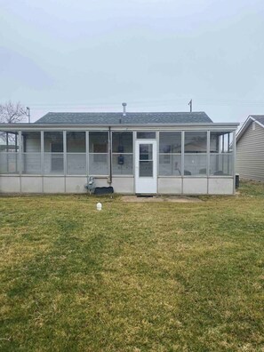 A single-story building with a covered patio area, a door, and a small window.