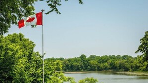A lakeside setting with red Adirondack chairs and a flagpole with a Canadian flag. - River front paradise,  boat, kayak, swim,  go to the racetrack, have fun, relax! (Cayuga)
