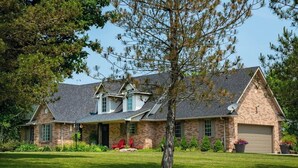 A two-story house with a stone facade, a large front lawn, and a garage. - River front paradise,  boat, kayak, swim,  go to the racetrack, have fun, relax! (Cayuga)