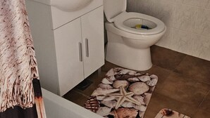 Une salle de bain avec un lavabo blanc, des toilettes et des murs carrelés.