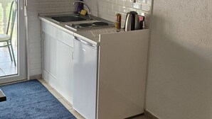 Une cuisine de taille réduite, équipée d’un évier, d’une cuisinière et d’un réfrigérateur.
