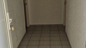 A narrow hallway with tiled flooring and a door on the left.