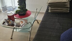 A glass coffee table with a tray, a small potted plant, and a red bowl on it.