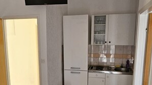 A compact kitchen with white cabinets, a stainless steel sink, and a tiled backsplash.
