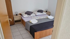 A bedroom with a bed, two bedside tables, a nightstand, and a wardrobe.