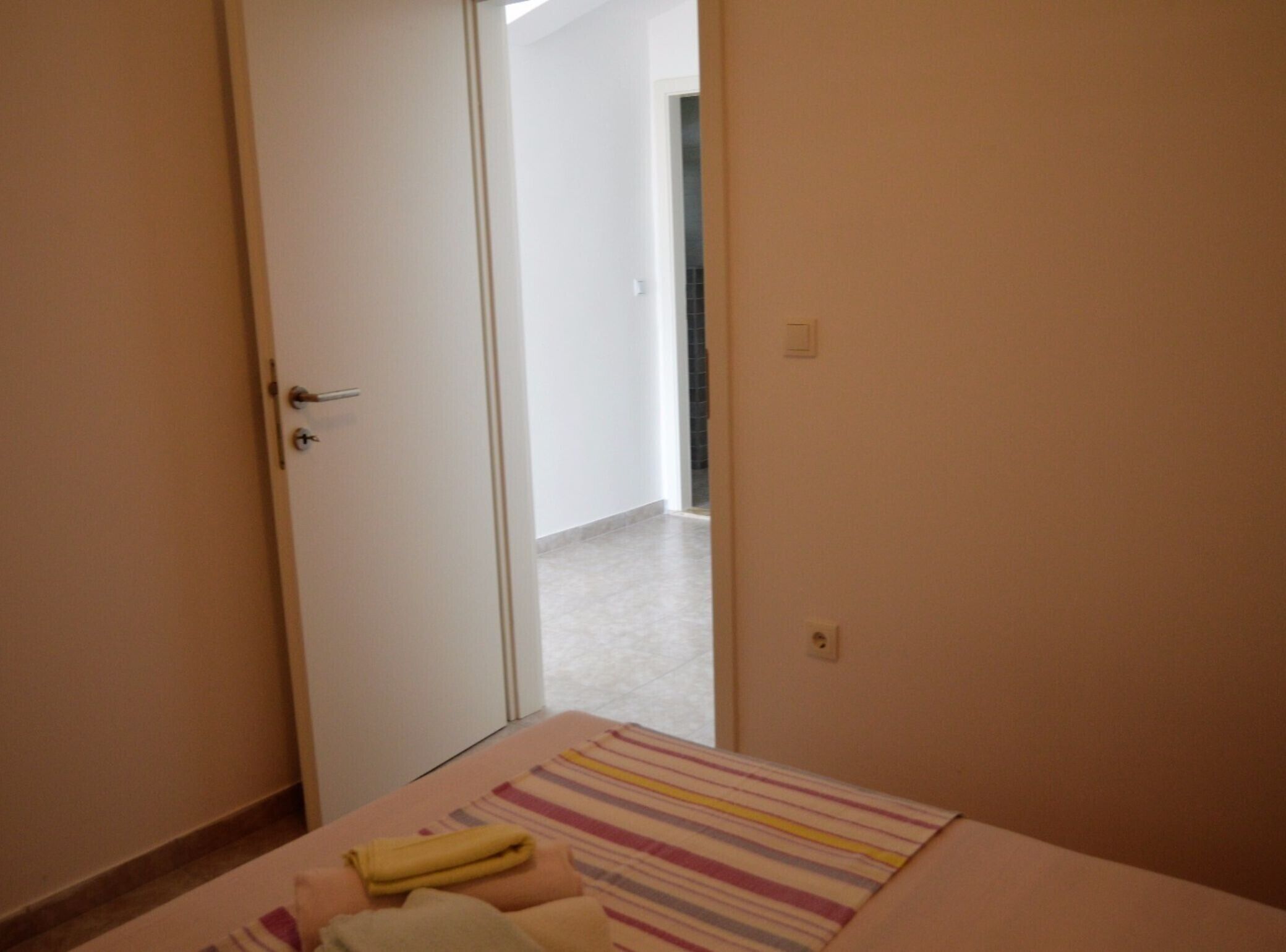 A bedroom with a bed, a striped blanket, and a door leading to another room.