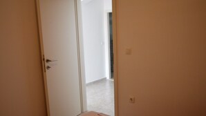 Ein Schlafzimmer mit einem Bett, einer gestreiften Decke und einer Tür zu einem anderen Raum.
